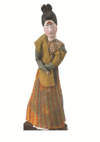 唐，木身锦衣裙女俑。女俑为木胎加彩，头挽高髻，阔眉细目，额饰花钿，颊敷红粉，在眼角外下侧各饰