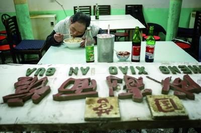 结束营业后，标有“国营”二字的老招牌被抬进屋里，即将离开的工作人员吃着最后一顿工作餐 摄/法制晚报记者 黑克